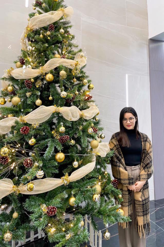 a girl standing by the christmas tree